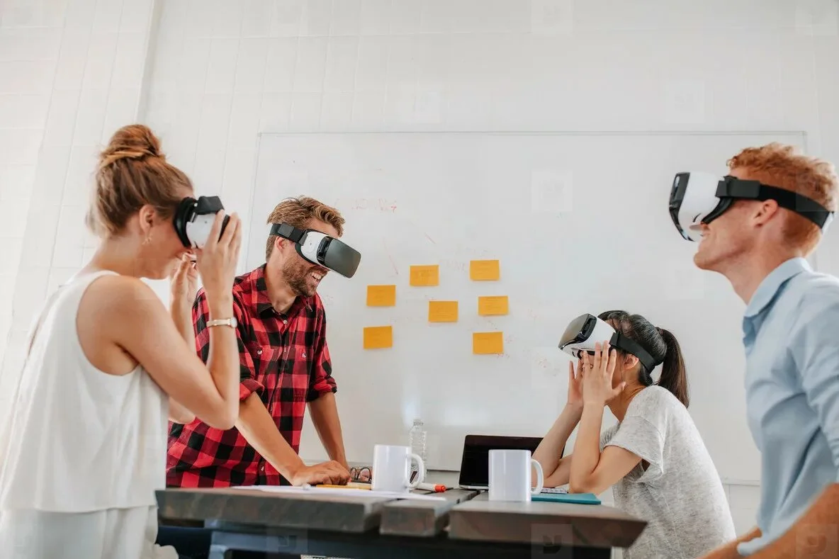 A team of developers collaborating around a desk with VR headsets.